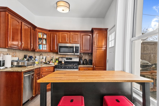 206A 29th St, New York City, NY 11232 - kitchen with a healthy amount of sunlight, a sink, decorative backsplash, a kitchen bar, and appliances with stainless steel finishes