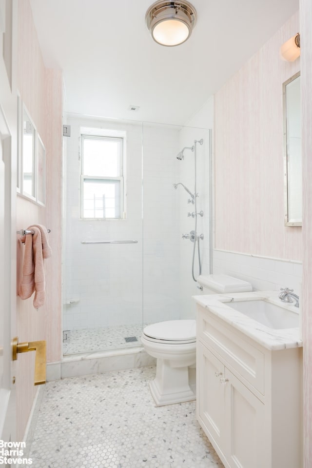 bathroom featuring a shower stall, wallpapered walls, toilet, and vanity