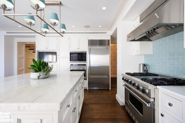 kitchen with exhaust hood, built in appliances, decorative backsplash, white cabinets, and light stone counters