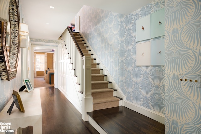 staircase featuring wallpapered walls, wood finished floors, and baseboards