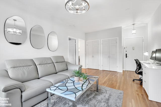 living area featuring a chandelier, light wood-style flooring, and an office area