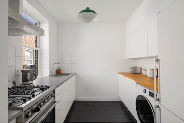 kitchen featuring washer / clothes dryer, a sink, freestanding refrigerator, under cabinet range hood, and high end stainless steel range