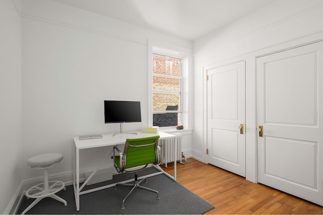 office space featuring radiator, light wood-style flooring, and baseboards