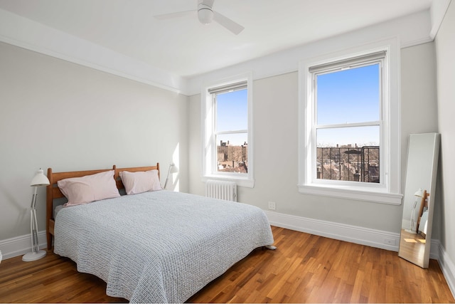 bedroom with ceiling fan, radiator heating unit, wood finished floors, and baseboards