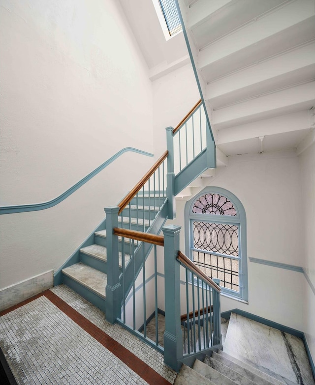 stairway featuring a high ceiling and baseboards