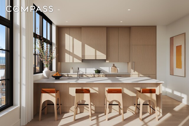 kitchen with modern cabinets, a kitchen bar, light wood-style floors, a peninsula, and light countertops