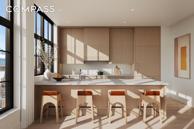 201 E 23rd St Unit 17A, New York City, NY 10010 - kitchen featuring modern cabinets, a breakfast bar, light wood-type flooring, a peninsula, and light countertops