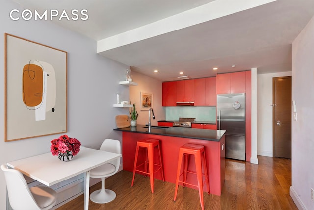 954 Bergen St Unit 5D, New York City, NY 11216 - kitchen with appliances with stainless steel finishes, wood finished floors, dark countertops, a peninsula, and recessed lighting
