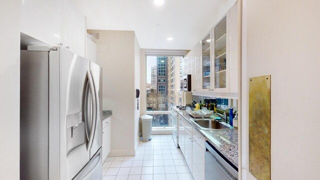 845 United Nations Plz Unit 7-H, New York City, NY 10017 - kitchen featuring stainless steel appliances, glass insert cabinets, white cabinetry, light tile patterned floors, and recessed lighting