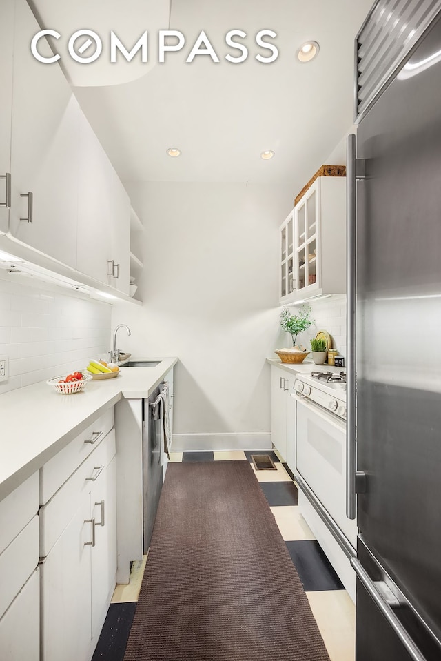 kitchen featuring backsplash, open shelves, stainless steel appliances, and a sink