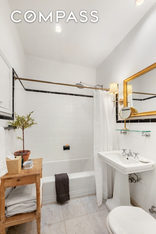 bathroom featuring marble finish floor, toilet, and shower / tub combo with curtain