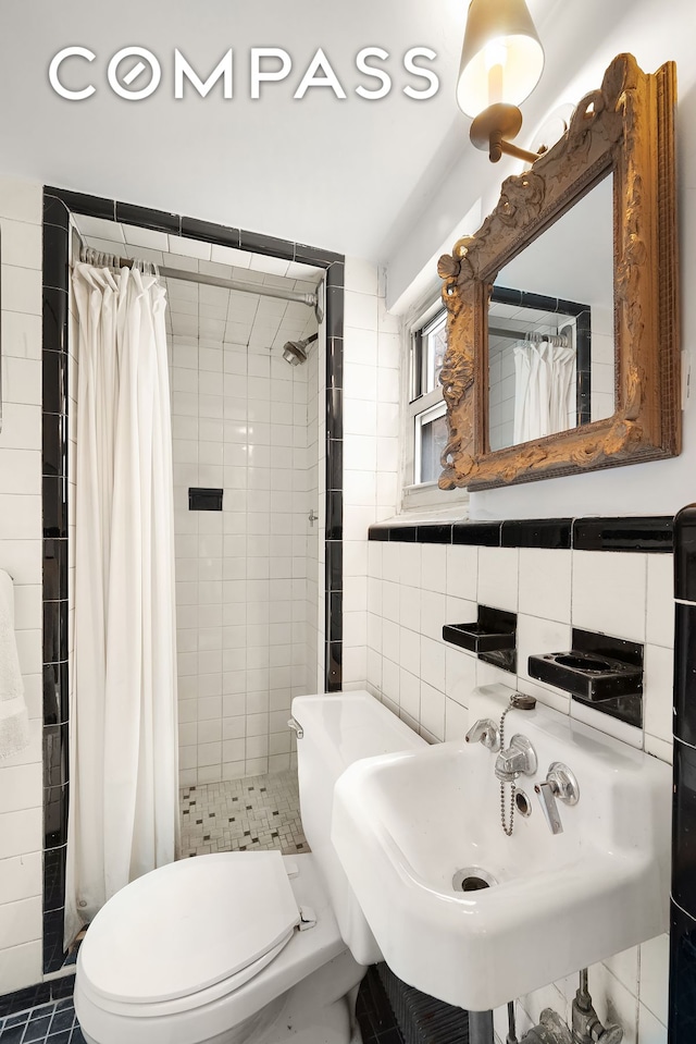 bathroom with tile walls, toilet, a stall shower, and a sink