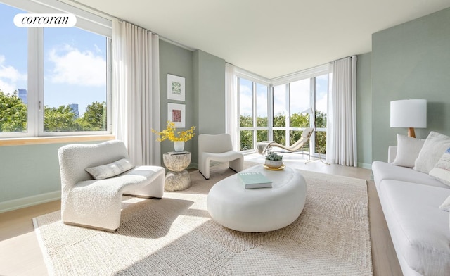 living area featuring baseboards, wood finished floors, and floor to ceiling windows