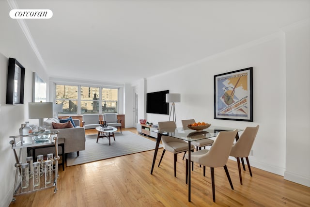 dining room featuring baseboards, visible vents, light wood-type flooring, and crown molding