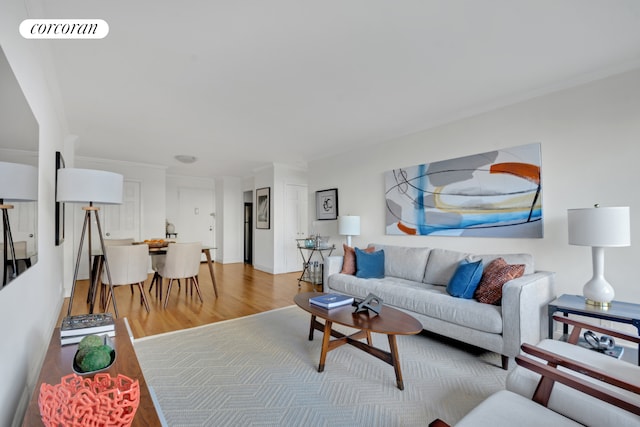 living room featuring crown molding, light wood finished floors, and visible vents