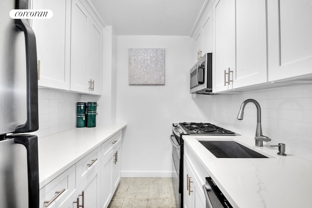 kitchen featuring stainless steel microwave, baseboards, backsplash, and freestanding refrigerator