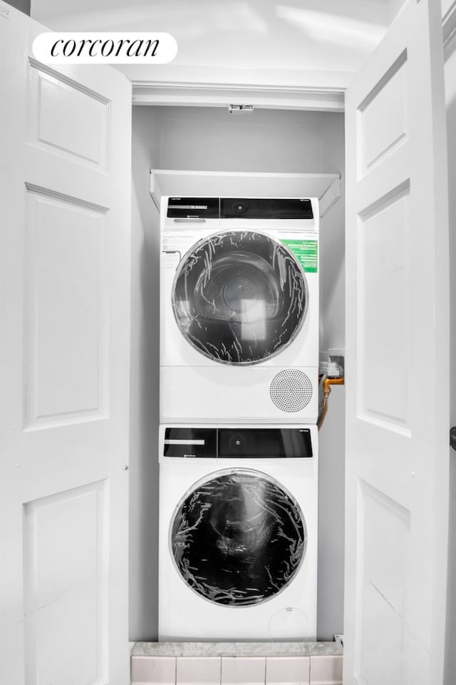 clothes washing area with stacked washing maching and dryer and laundry area