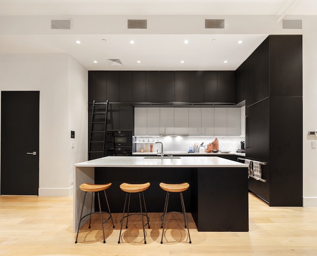 121 Mercer St Unit 4-Flr, New York City, NY 10012 - kitchen with modern cabinets, dark cabinetry, a sink, light wood-style floors, and recessed lighting