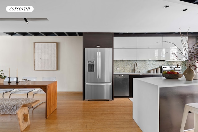 126 2nd St, New York City, NY 11231 - kitchen with decorative backsplash, light wood-style floors, light countertops, a sink, and appliances with stainless steel finishes