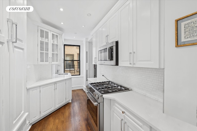 545 W End Ave Unit 7Ef, New York City, NY 10024 - kitchen featuring glass insert cabinets, white cabinetry, dark wood-style flooring, and stainless steel appliances