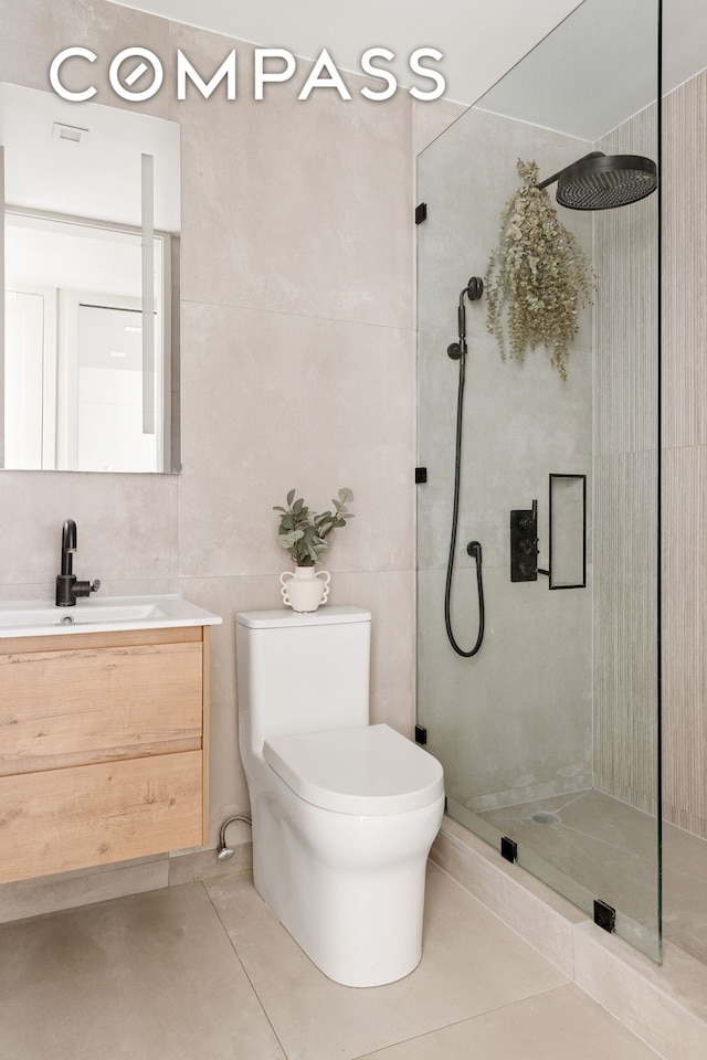full bath featuring a stall shower, tile patterned flooring, toilet, vanity, and tile walls