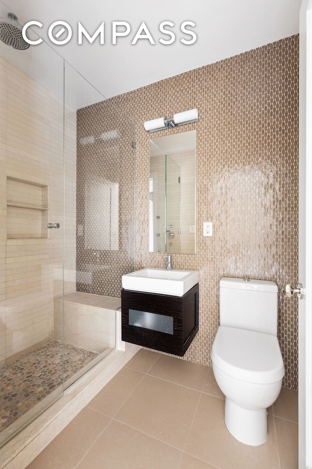 180 E 79th St Unit 14G, New York City, NY 10075 - bathroom with tile patterned floors, tile walls, a shower stall, toilet, and vanity