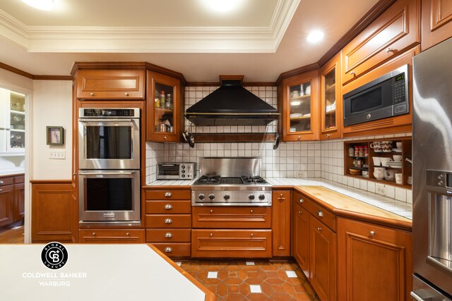 170 E 79th St Unit 9/10B, New York City, NY 10075 - kitchen with stainless steel appliances, premium range hood, decorative backsplash, brown cabinetry, and crown molding
