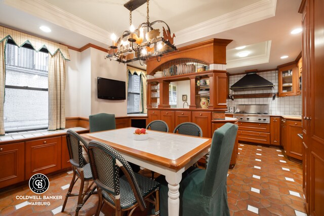 170 E 79th St Unit 9/10B, New York City, NY 10075 - dining area featuring ornamental molding, a chandelier, a raised ceiling, a wainscoted wall, and recessed lighting