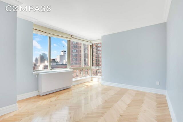 unfurnished room featuring a view of city, baseboards, and ornamental molding