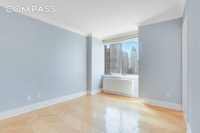 spare room with baseboards, ornamental molding, and a view of city