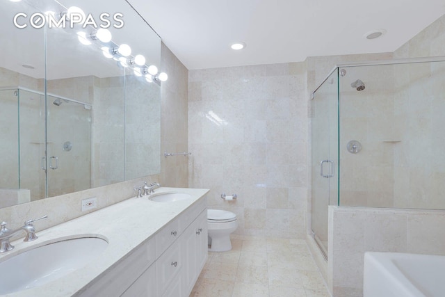 full bath featuring a sink, tile walls, a shower stall, and double vanity
