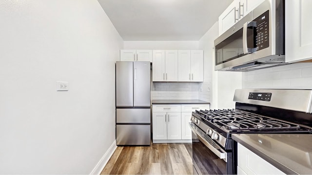 3500 Snyder Ave Unit 4R, New York City, NY 11203 - kitchen featuring appliances with stainless steel finishes, dark countertops, light wood-style flooring, white cabinetry, and backsplash