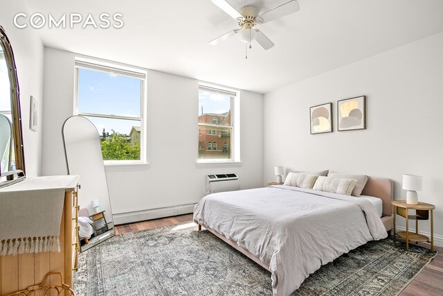127 4th Pl Unit 2A, New York City, NY 11231 - bedroom with baseboard heating, wood finished floors, a wall mounted air conditioner, a ceiling fan, and baseboards