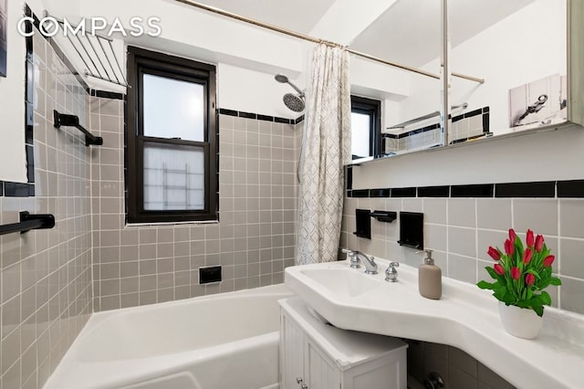 full bath with a sink, decorative backsplash, shower / bath combination with curtain, and tile walls