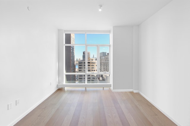 5 Beekman St Unit 22C, New York City, NY 10038 - spare room featuring baseboards, a city view, hardwood / wood-style floors, and expansive windows