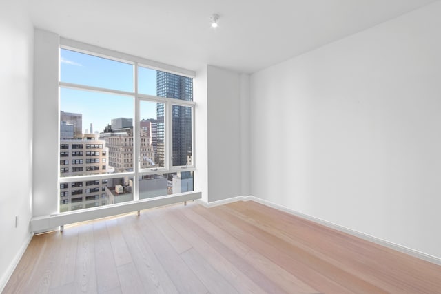 5 Beekman St Unit 22C, New York City, NY 10038 - spare room featuring expansive windows, a view of city, baseboards, and wood finished floors