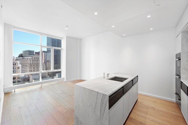 5 Beekman St Unit 22C, New York City, NY 10038 - kitchen featuring a view of city, light stone countertops, a wall of windows, a sink, and light wood finished floors