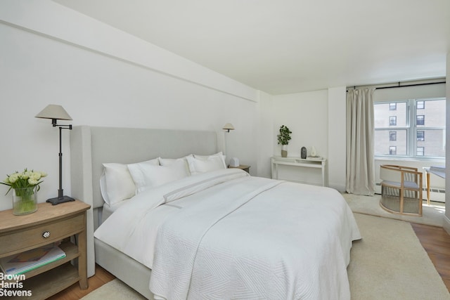 bedroom featuring baseboard heating and wood finished floors