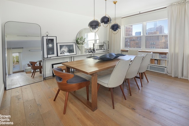 dining area with light wood-style floors, an inviting chandelier, and a city view