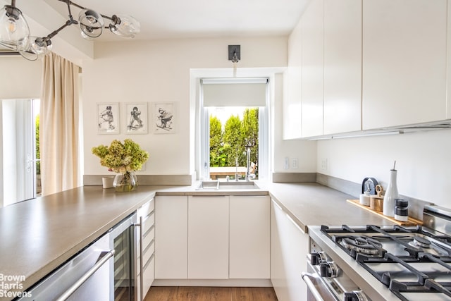 kitchen with modern cabinets, gas stove, a sink, white cabinets, and wine cooler