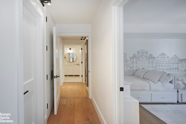 corridor with baseboards and light wood finished floors