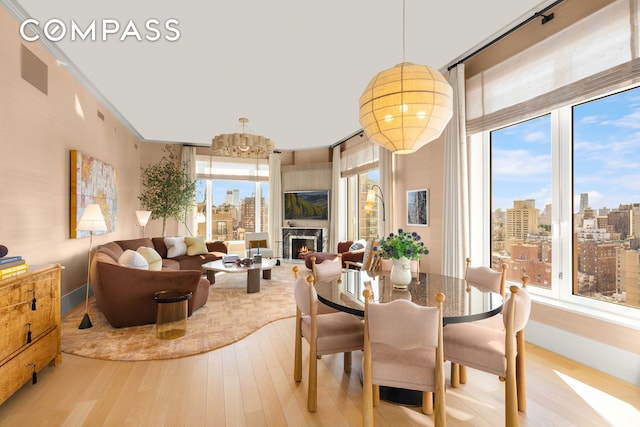 200 E 83rd St Unit 24C, New York City, NY 10028 - dining room with wood finished floors, a chandelier, a lit fireplace, and baseboards