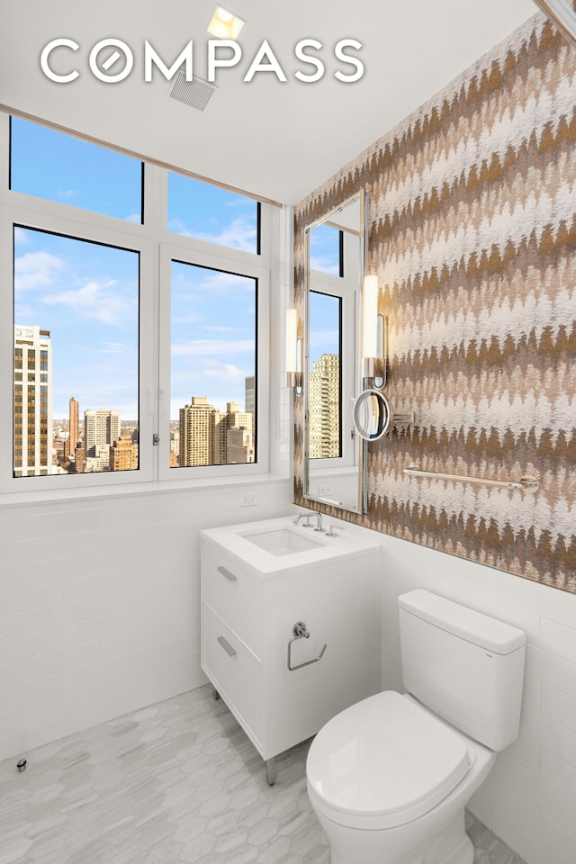 200 E 83rd St Unit 24C, New York City, NY 10028 - half bathroom featuring toilet, vanity, a city view, and tile walls