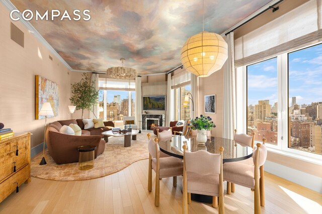 200 E 83rd St Unit 24C, New York City, NY 10028 - dining space with wood finished floors, a chandelier, a fireplace, crown molding, and baseboards