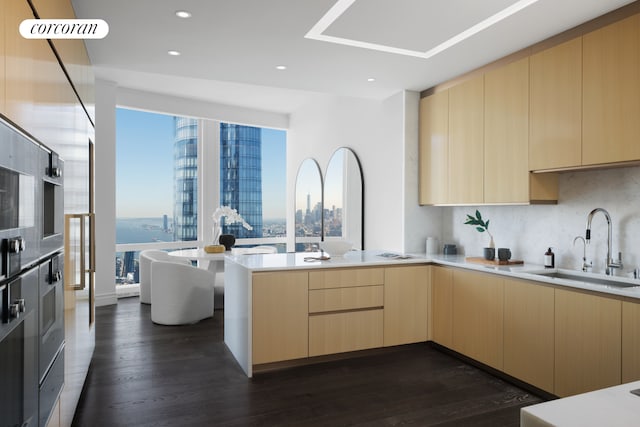 kitchen featuring a view of city, a peninsula, modern cabinets, a sink, and light brown cabinetry
