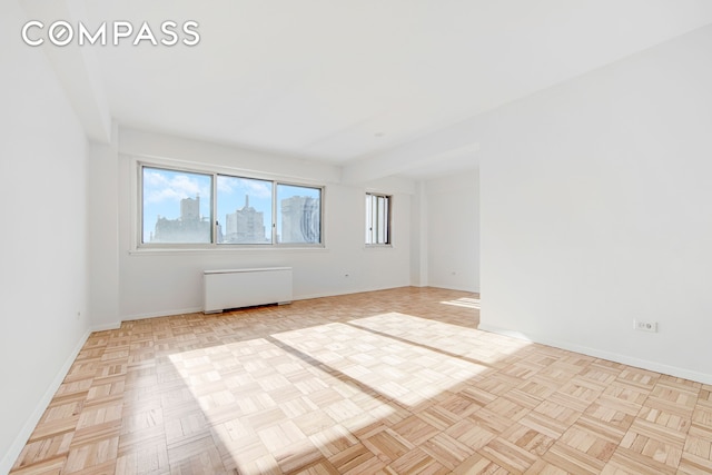 unfurnished room with radiator heating unit and baseboards