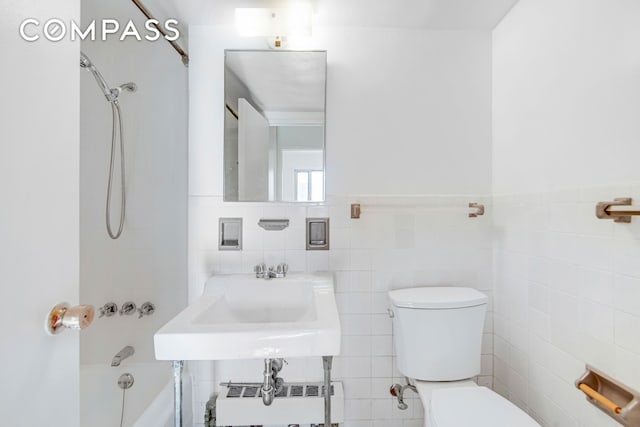 bathroom with tile walls, a sink, toilet, radiator, and bathing tub / shower combination