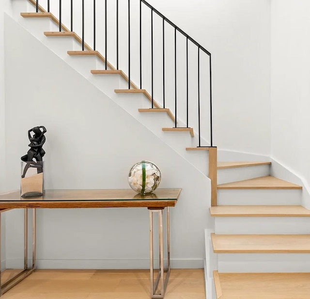 staircase featuring wood finished floors and baseboards