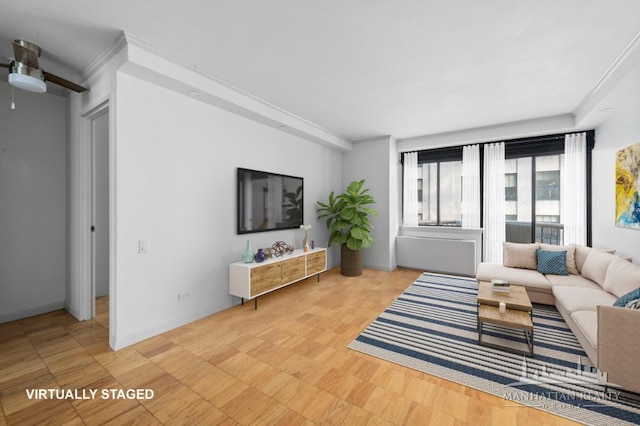 living area with a ceiling fan, ornamental molding, and baseboards