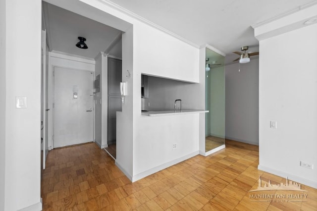 kitchen with a ceiling fan, crown molding, baseboards, and light countertops